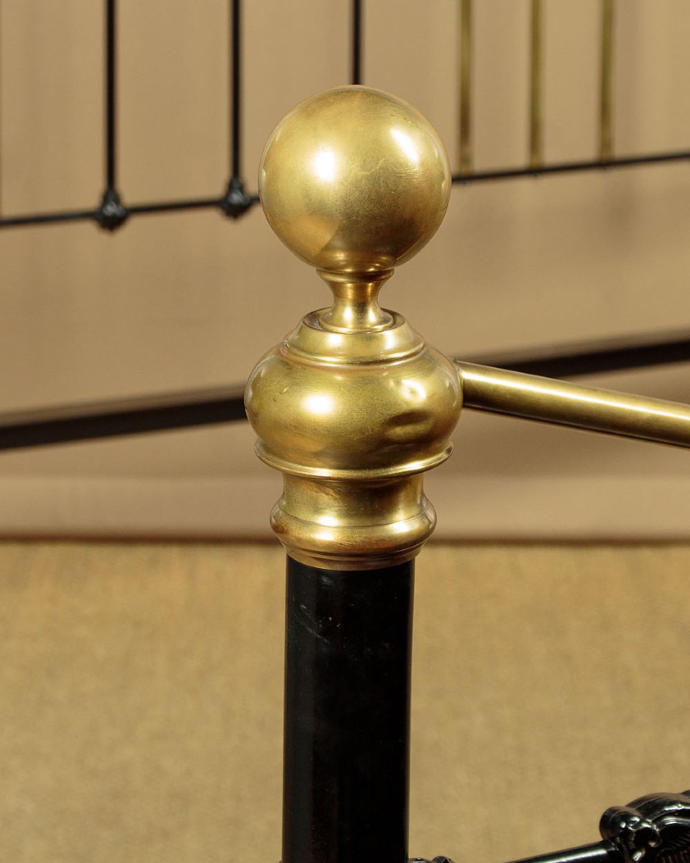 A late Victorian black iron and brass king-size bed frame featuring decorative brass finials, a dipped brass top rail, and vertical spindles. View V