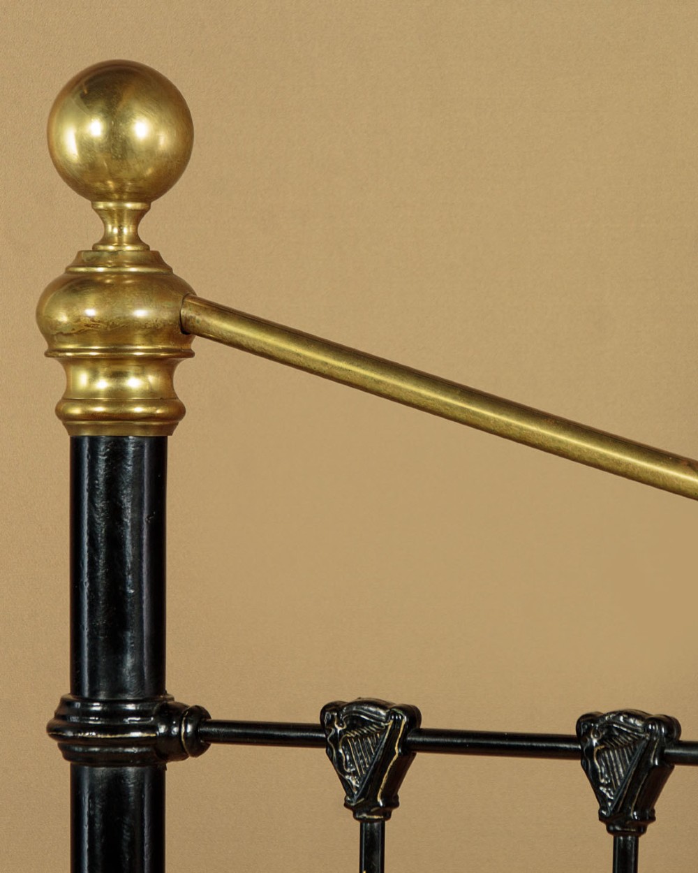 A late Victorian black iron and brass king-size bed frame featuring decorative brass finials, a dipped brass top rail, and vertical spindles. View VI