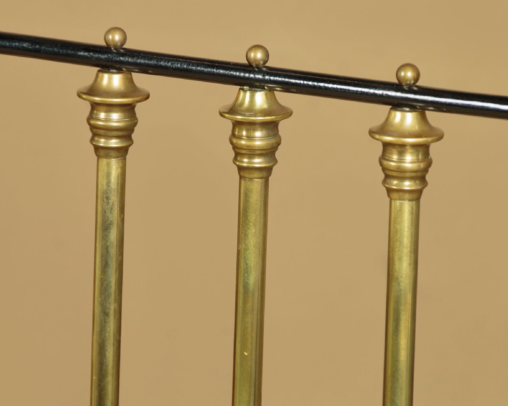 A late Victorian black iron and brass king-size bed frame featuring decorative brass finials, a dipped brass top rail, and vertical spindles. View VII
