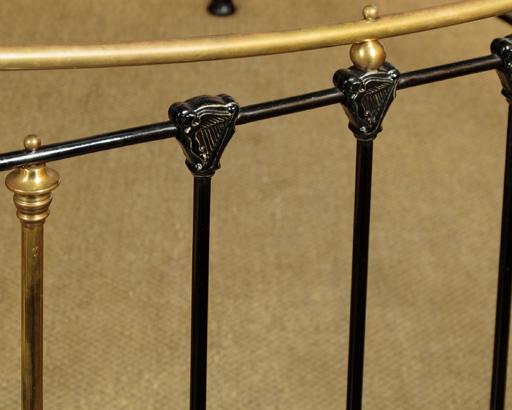 A late Victorian black iron and brass king-size bed frame featuring decorative brass finials, a dipped brass top rail, and vertical spindles. View VIII