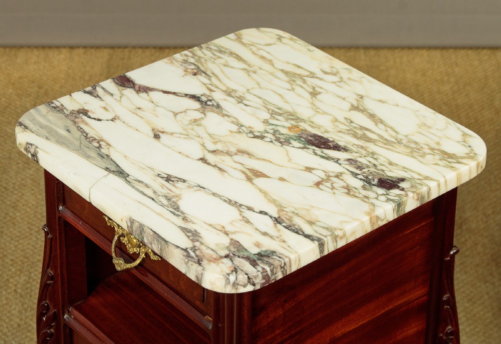 A pair of late 19th-century mahogany bedside cabinets featuring variegated marble tops, single upper drawers, open shelf recesses, and lower cupboards supported on cabriole legs. View V