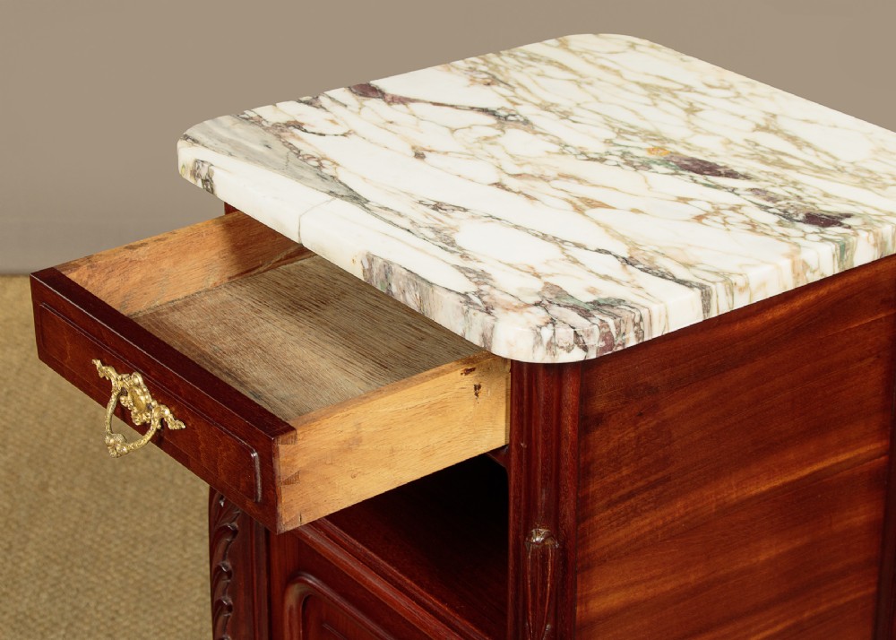 A pair of late 19th-century mahogany bedside cabinets featuring variegated marble tops, single upper drawers, open shelf recesses, and lower cupboards supported on cabriole legs. View VI