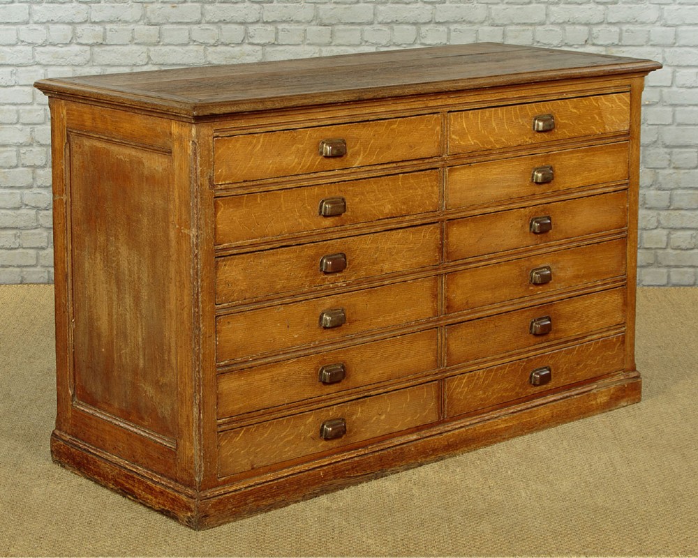 An Edwardian golden oak bank of twelve drawers featuring brass cup handles arranged in two vertical columns. View II