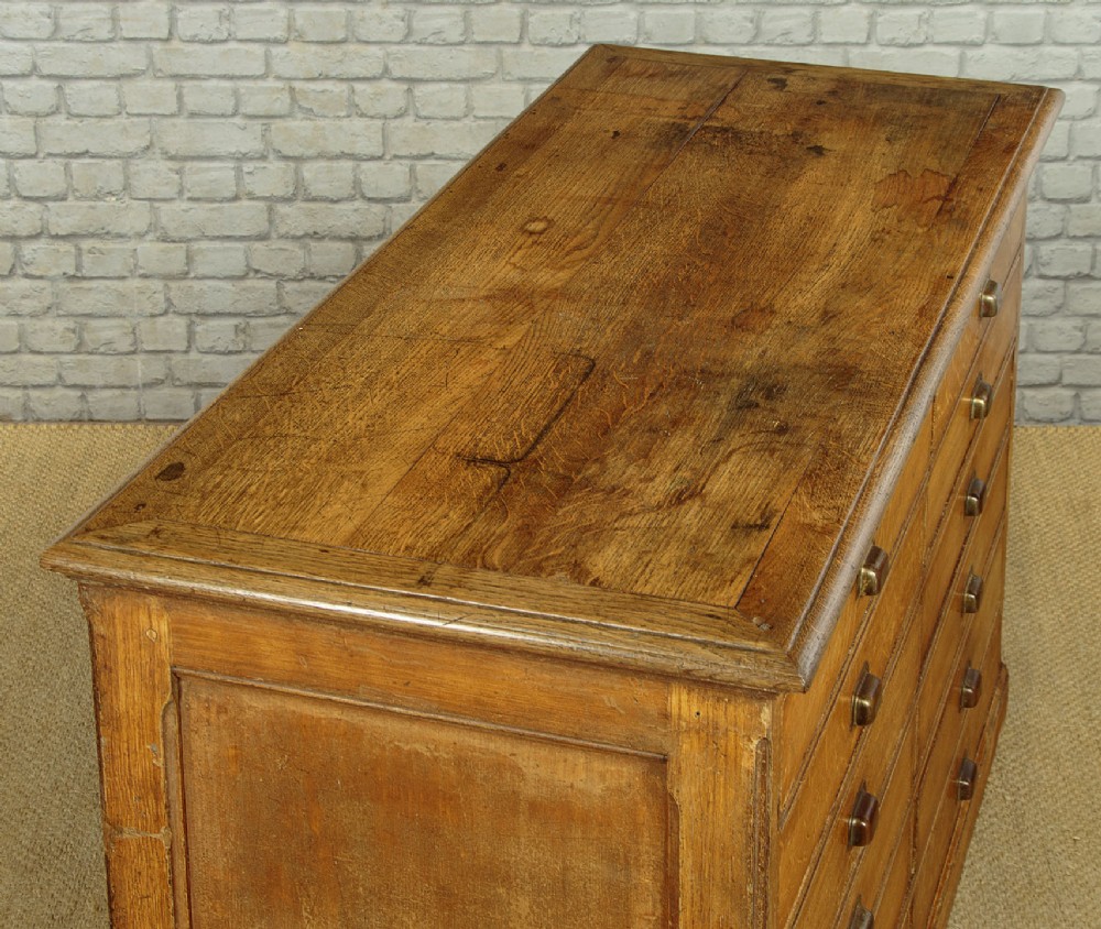 An Edwardian golden oak bank of twelve drawers featuring brass cup handles arranged in two vertical columns. View V