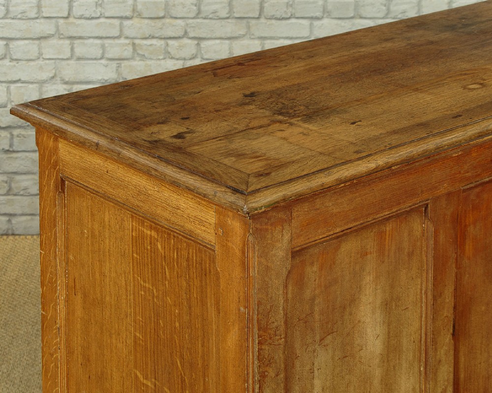 An Edwardian golden oak bank of twelve drawers featuring brass cup handles arranged in two vertical columns. View VII