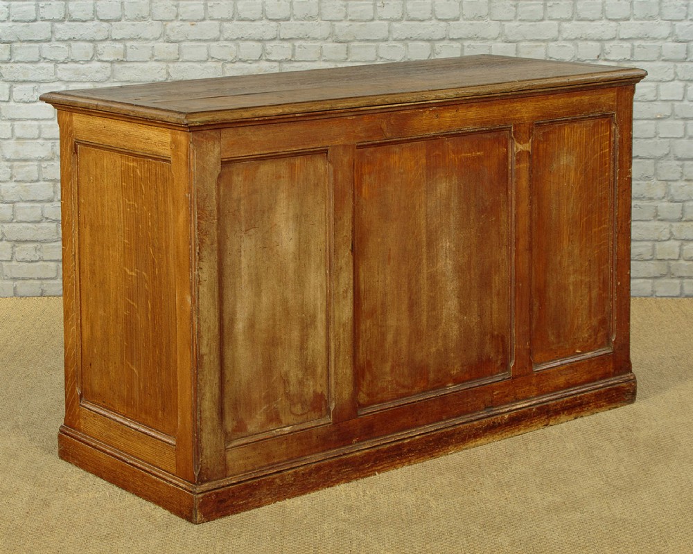 An Edwardian golden oak bank of twelve drawers featuring brass cup handles arranged in two vertical columns. View XI