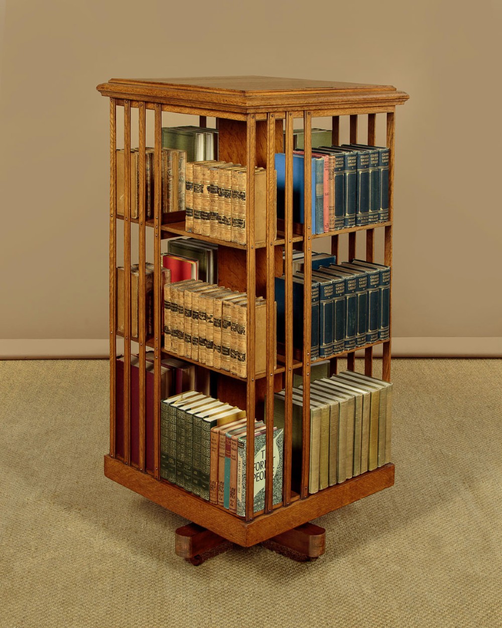 A three-tier Edwardian oak revolving bookcase featuring vertical slatted sides and a square moulded top resting on a rotating cross base. View II