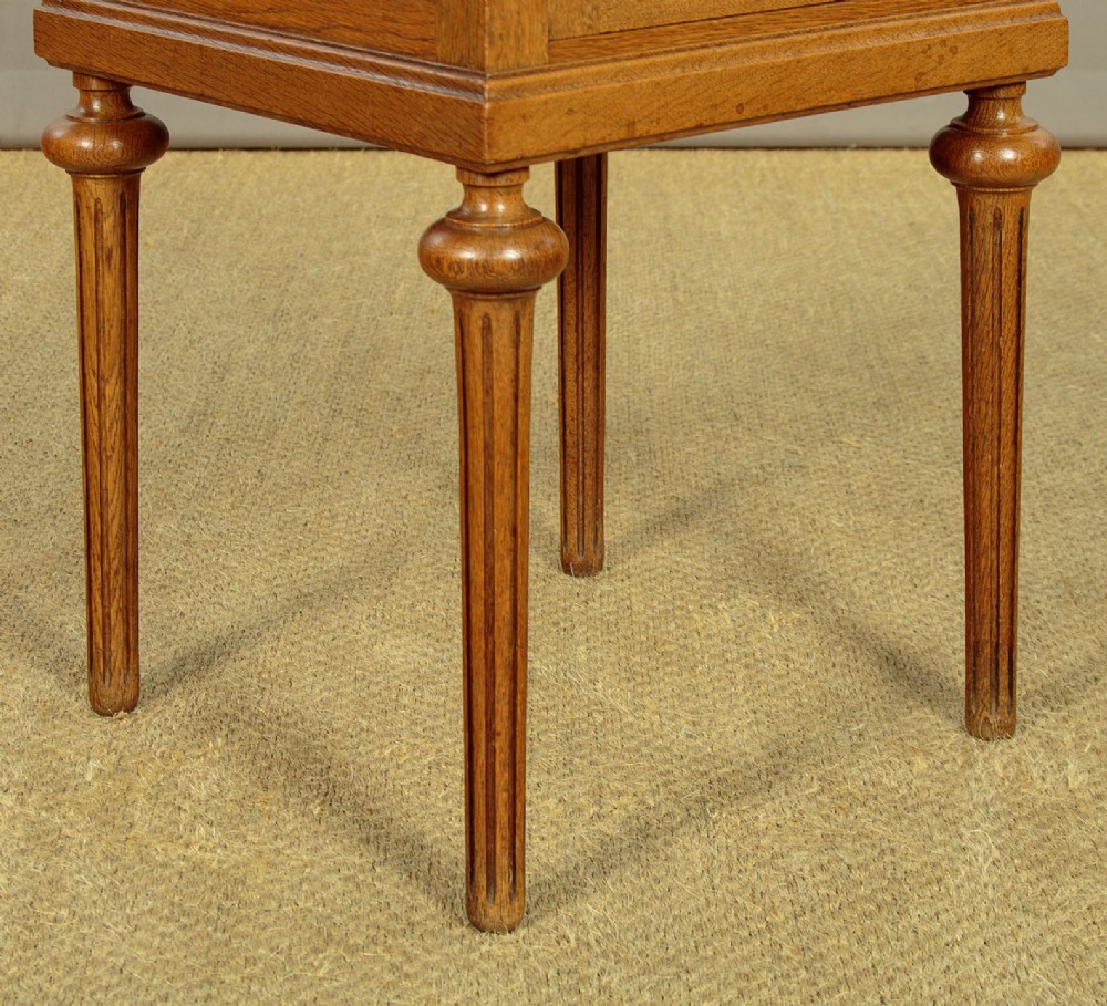 A pair of golden oak bedside cabinets featuring marble tops, single drawers, floral carved cupboard doors, and slim fluted turned legs. View XII