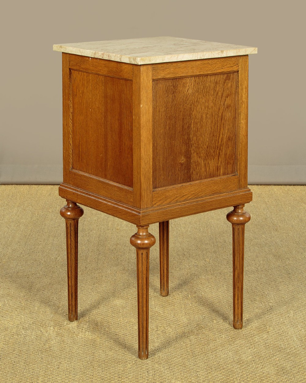 A pair of golden oak bedside cabinets featuring marble tops, single drawers, floral carved cupboard doors, and slim fluted turned legs. View XIII
