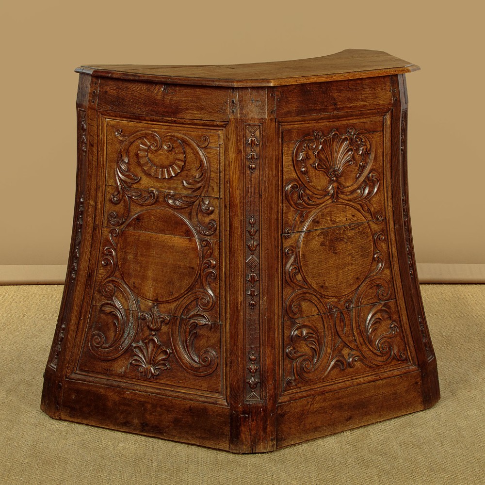 A faceted dark oak pulpit bar featuring carved relief panels with shell motifs and scrollwork. View III