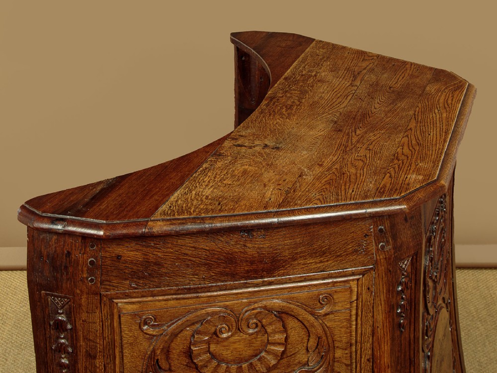 A faceted dark oak pulpit bar featuring carved relief panels with shell motifs and scrollwork. View VI