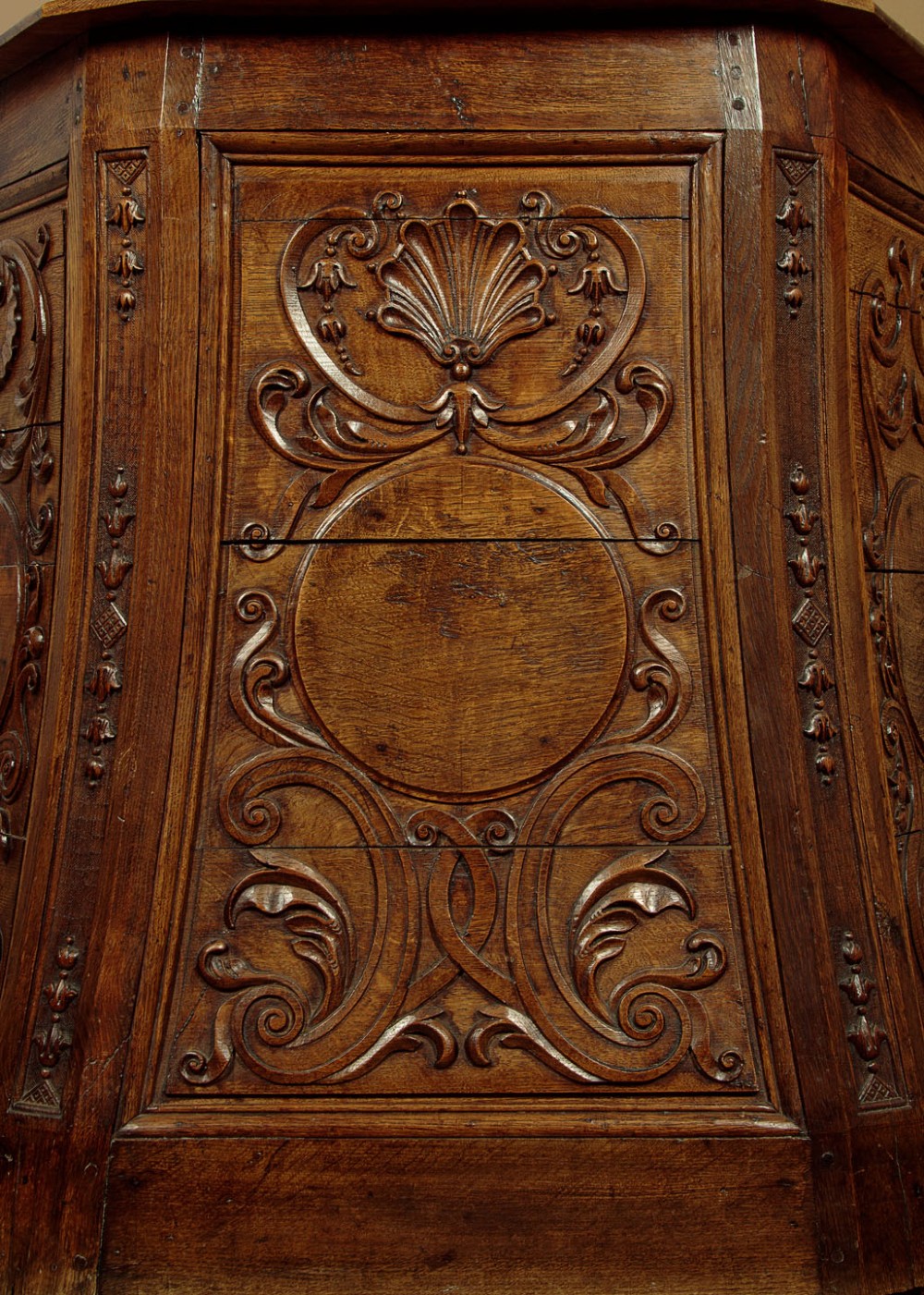 A faceted dark oak pulpit bar featuring carved relief panels with shell motifs and scrollwork. View VIII