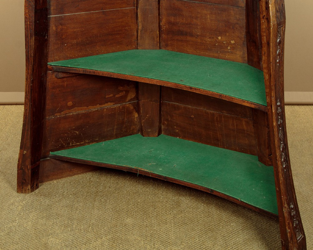 A faceted dark oak pulpit bar featuring carved relief panels with shell motifs and scrollwork. View X