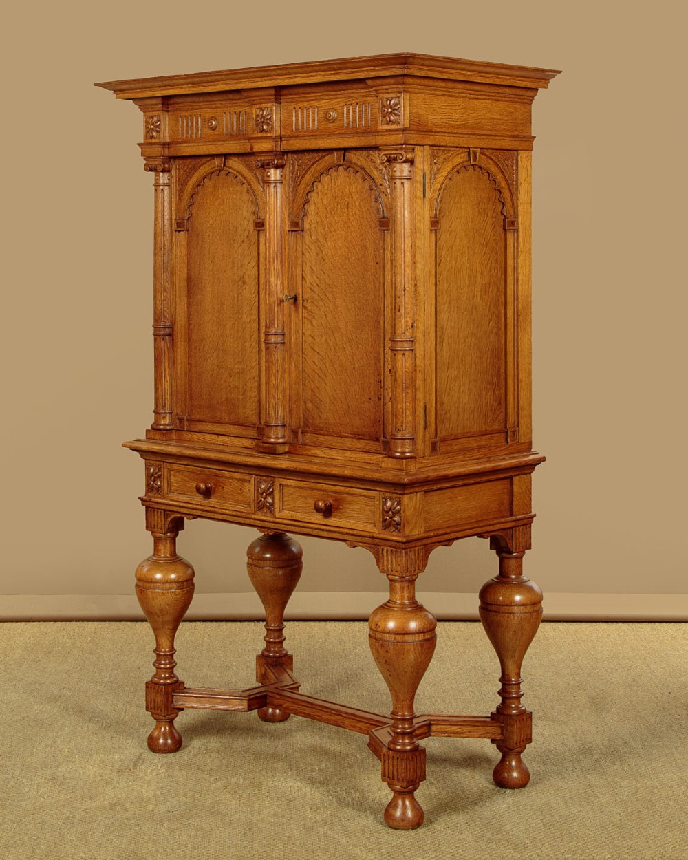A warm brown oak cabinet featuring arched doors set upon a matching stand with large turned bulbous legs and lower stretchers. View III