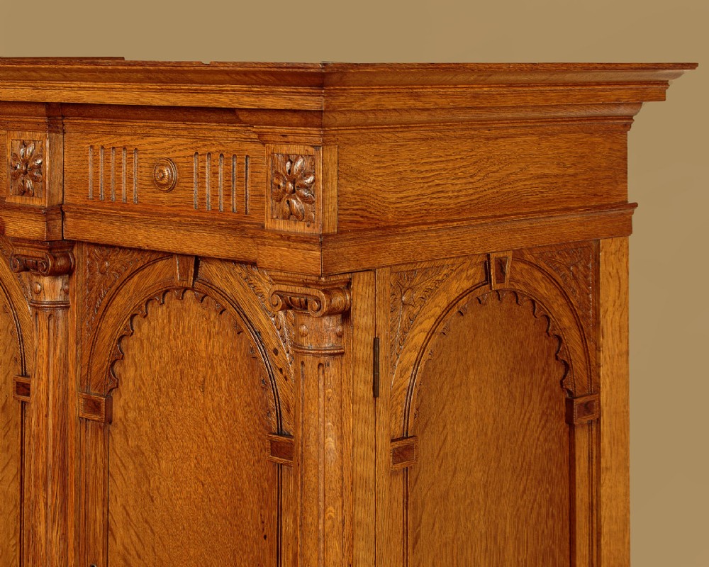 A warm brown oak cabinet featuring arched doors set upon a matching stand with large turned bulbous legs and lower stretchers. View V