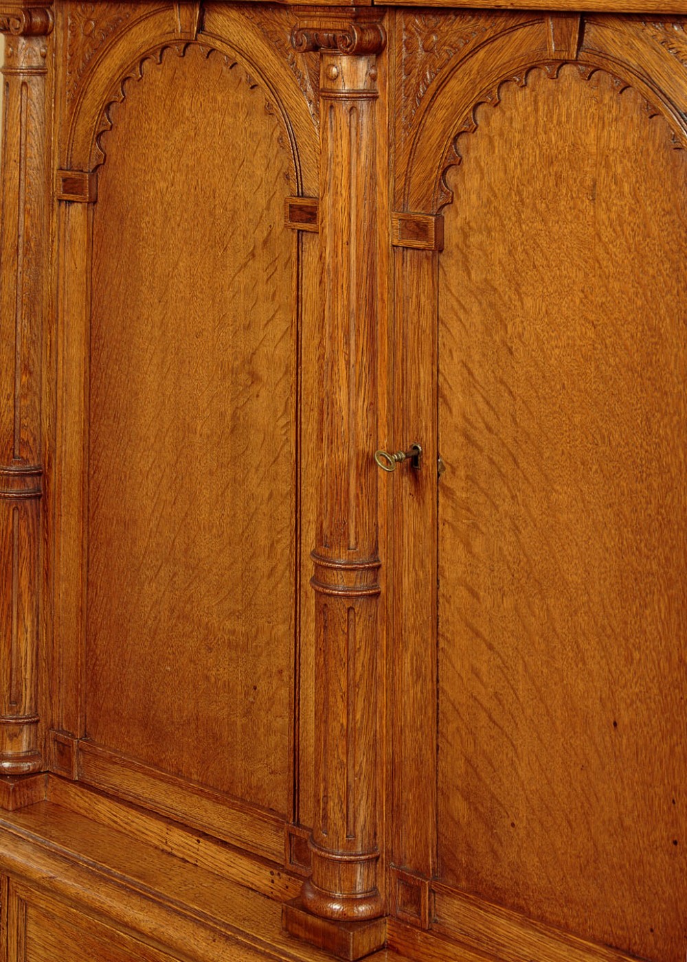 A warm brown oak cabinet featuring arched doors set upon a matching stand with large turned bulbous legs and lower stretchers. View VII