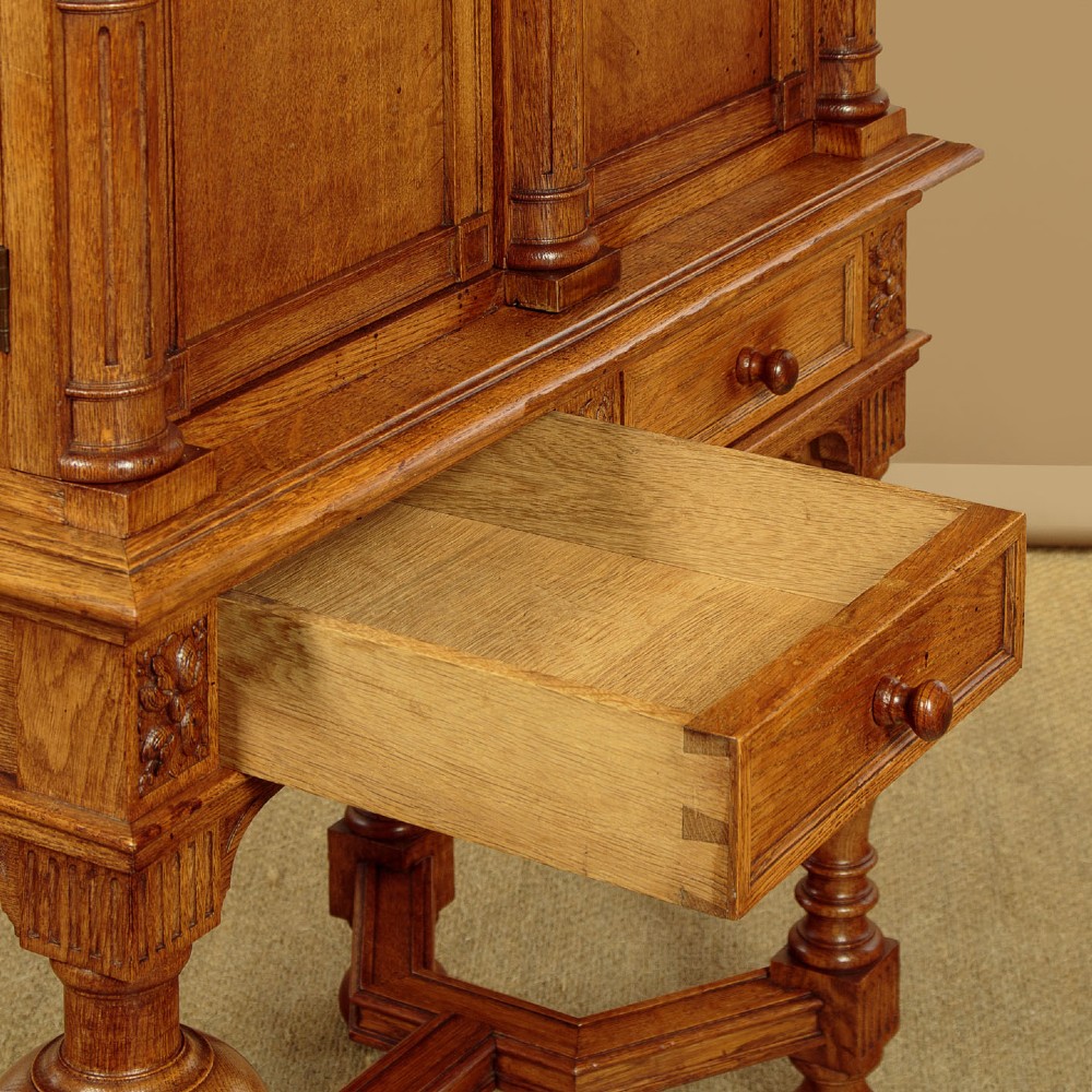 A warm brown oak cabinet featuring arched doors set upon a matching stand with large turned bulbous legs and lower stretchers. View X