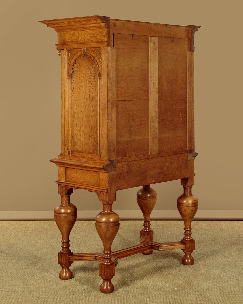 A warm brown oak cabinet featuring arched doors set upon a matching stand with large turned bulbous legs and lower stretchers. View XIII
