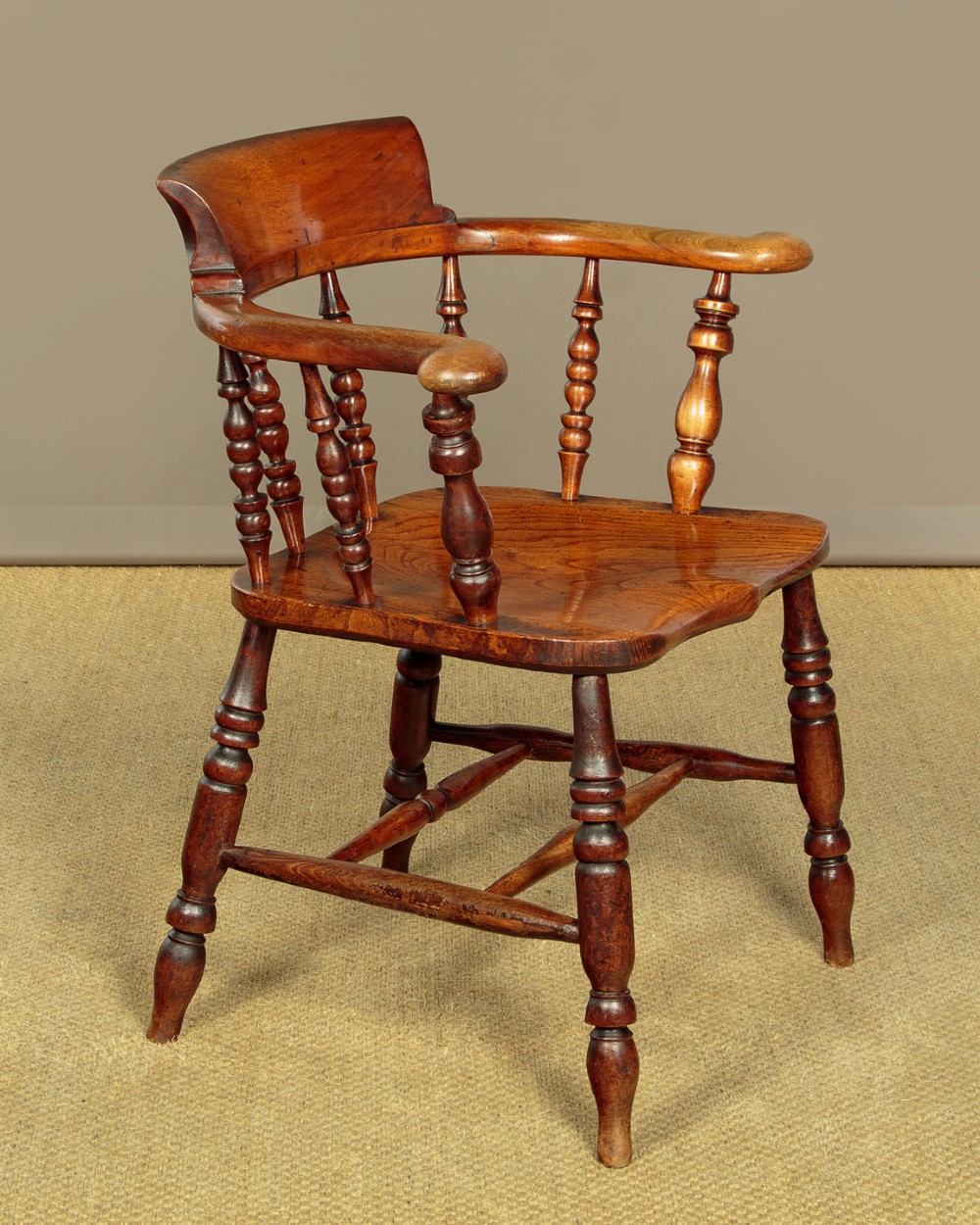 A Victorian smokers bow wooden armchair with turned spindles, a curved top rail, a contoured elm seat, and turned legs. View II