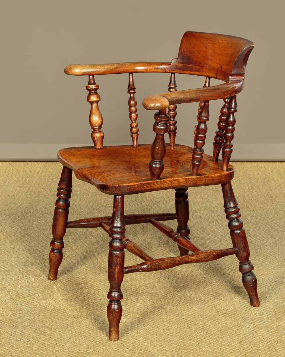 A Victorian smokers bow wooden armchair with turned spindles, a curved top rail, a contoured elm seat, and turned legs. View III