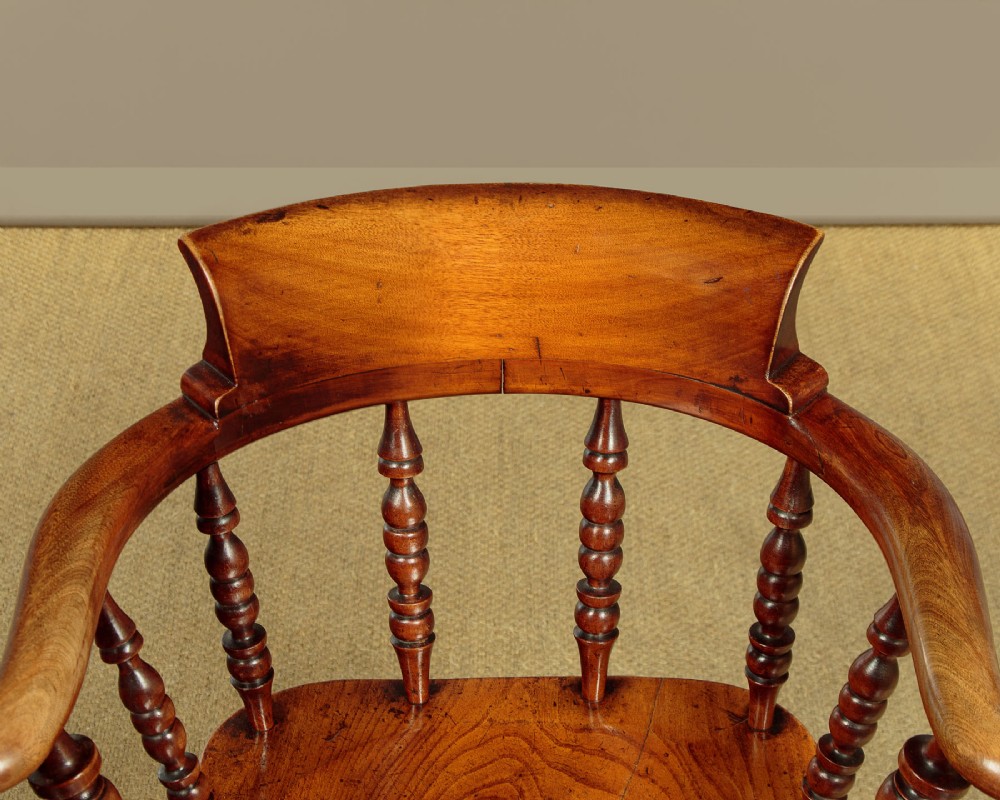 A Victorian smokers bow wooden armchair with turned spindles, a curved top rail, a contoured elm seat, and turned legs. View IV