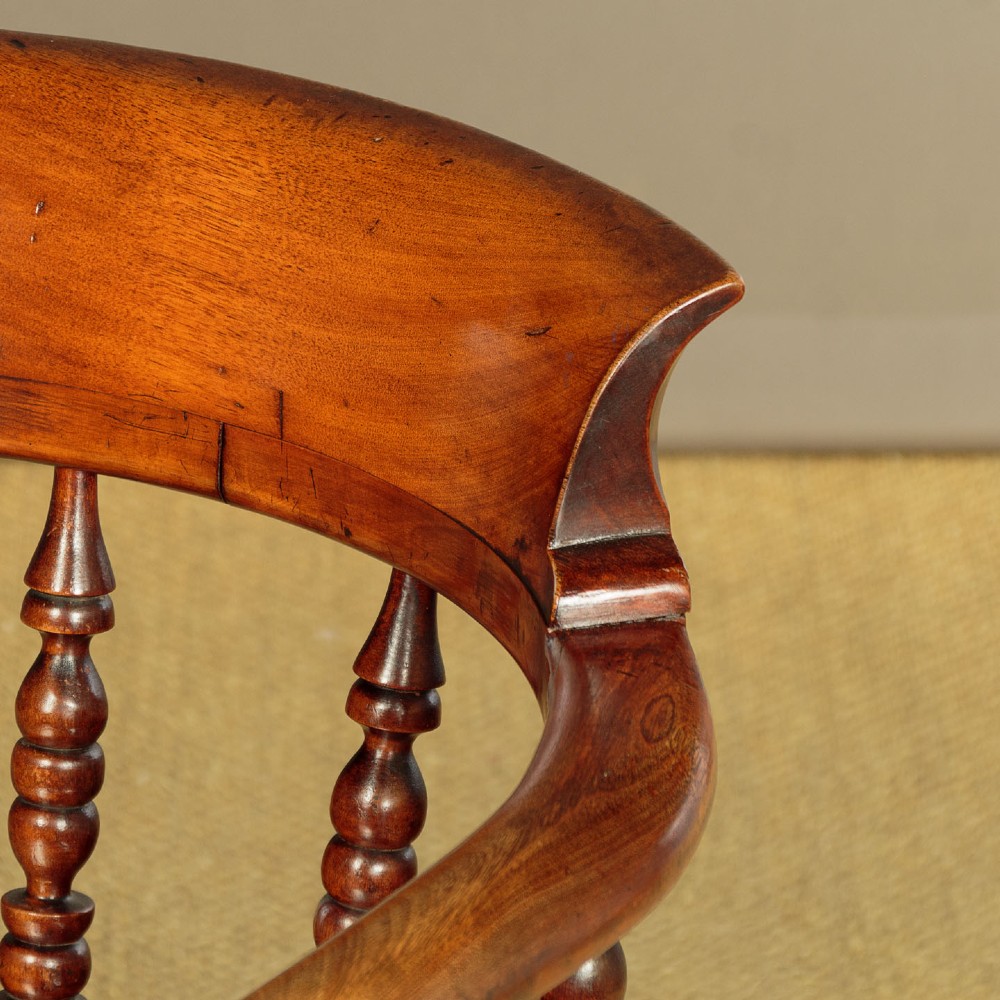 A Victorian smokers bow wooden armchair with turned spindles, a curved top rail, a contoured elm seat, and turned legs. View V