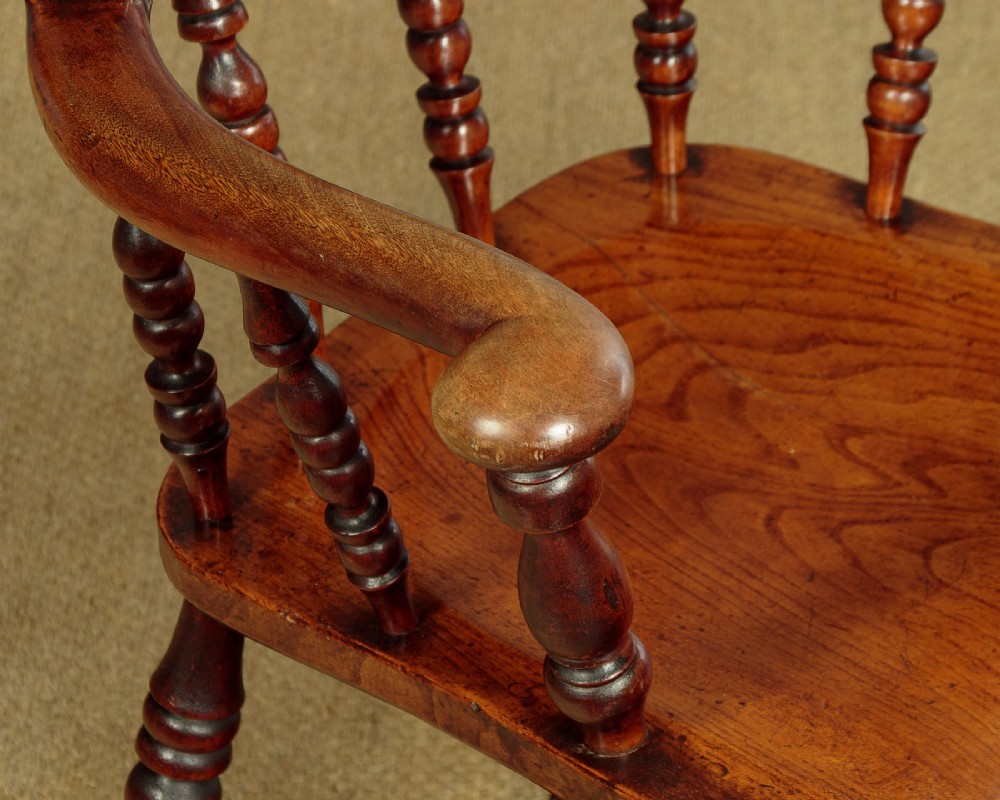 A Victorian smokers bow wooden armchair with turned spindles, a curved top rail, a contoured elm seat, and turned legs. View VI