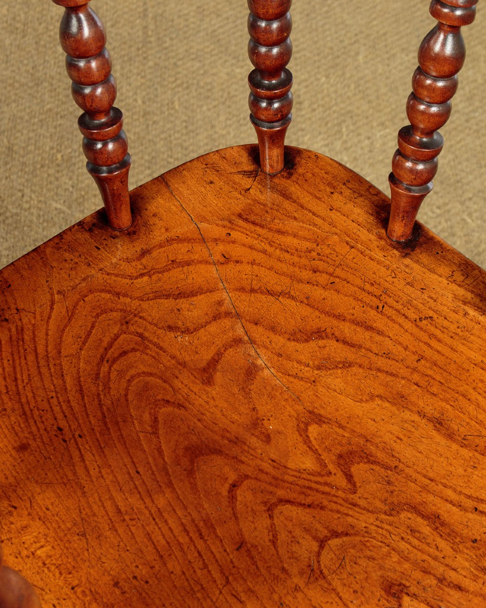 A Victorian smokers bow wooden armchair with turned spindles, a curved top rail, a contoured elm seat, and turned legs. View IX