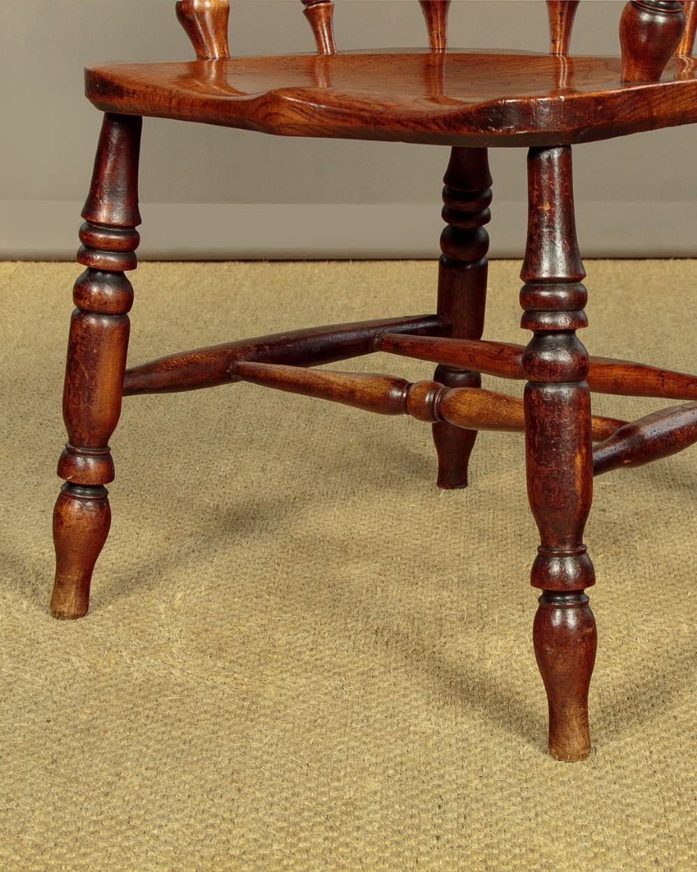 A Victorian smokers bow wooden armchair with turned spindles, a curved top rail, a contoured elm seat, and turned legs. View X