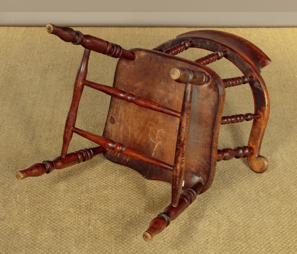 A Victorian smokers bow wooden armchair with turned spindles, a curved top rail, a contoured elm seat, and turned legs. View XII