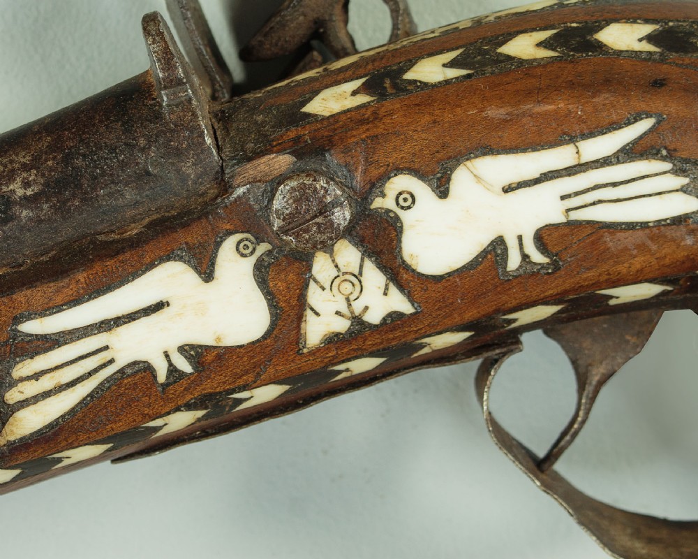 An antique Afghan Jezail musket featuring a distinctly curved wooden stock decorated with geometric bone inlay and a steel lock mechanism. View VI