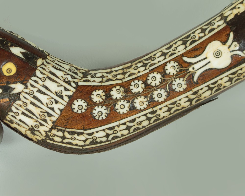 An antique Afghan Jezail musket featuring a distinctly curved wooden stock decorated with geometric bone inlay and a steel lock mechanism. View VII