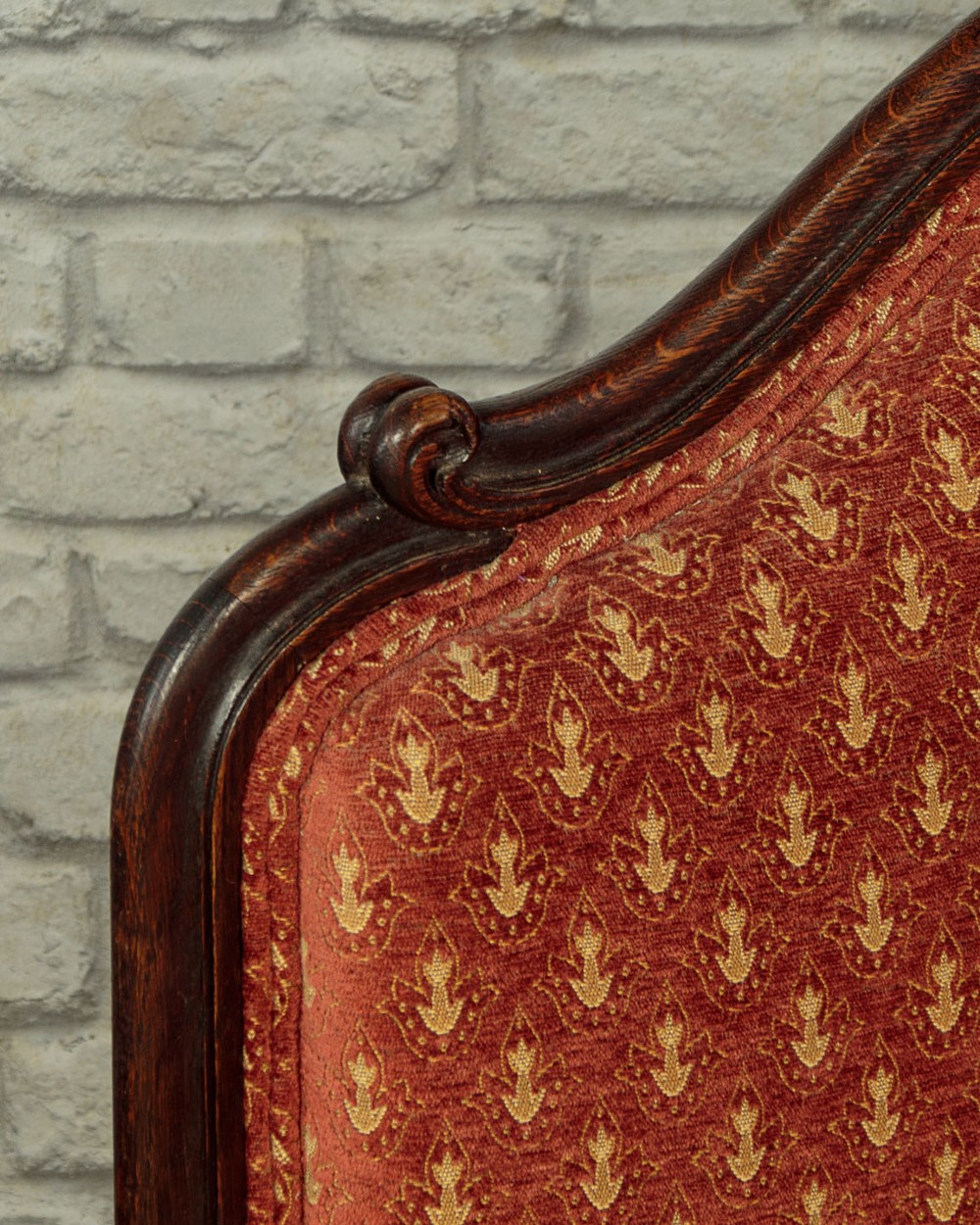 A c.1920 French-style upholstered day bed featuring a dark carved wooden frame, terracotta red patterned fabric, and matching tassel-trimmed cushions. View VII