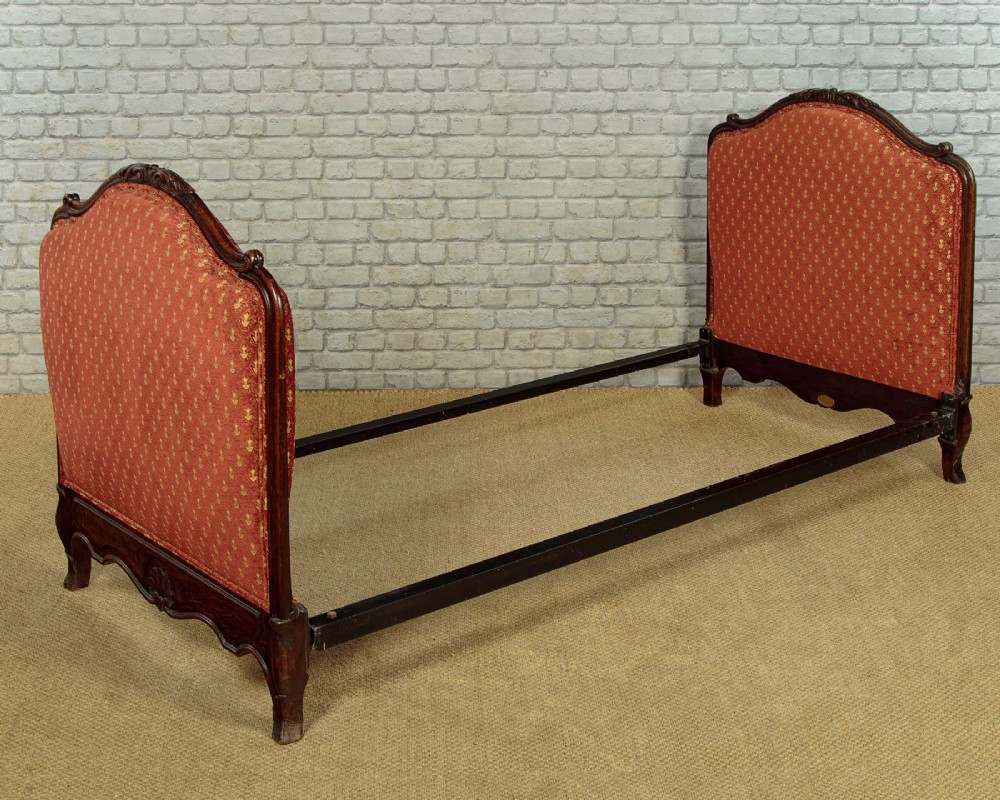 A c.1920 French-style upholstered day bed featuring a dark carved wooden frame, terracotta red patterned fabric, and matching tassel-trimmed cushions. View XI