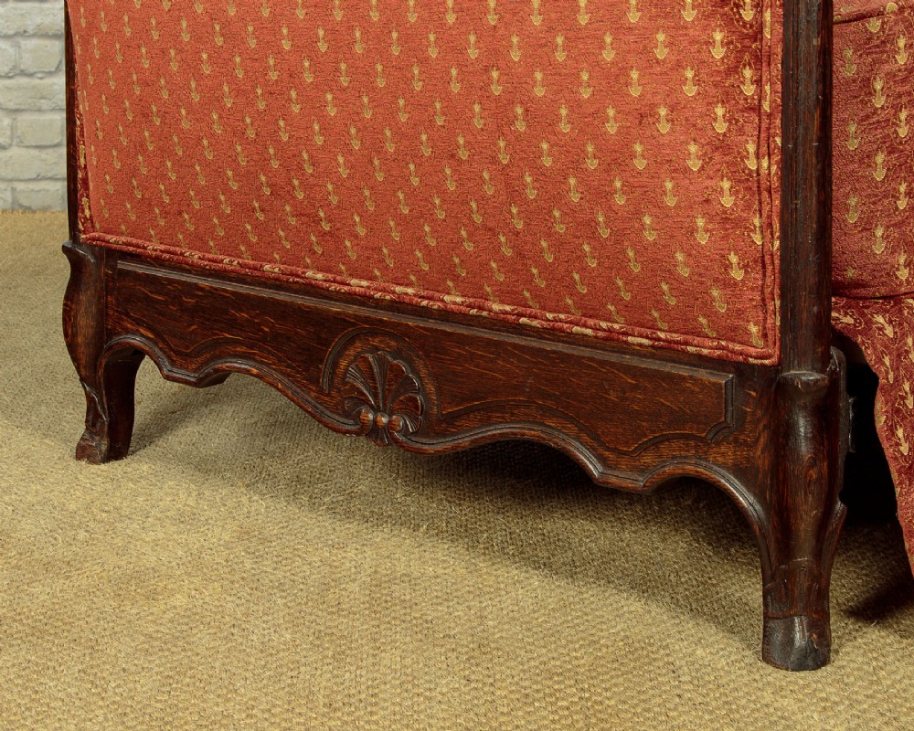 A c.1920 French-style upholstered day bed featuring a dark carved wooden frame, terracotta red patterned fabric, and matching tassel-trimmed cushions. View XIII