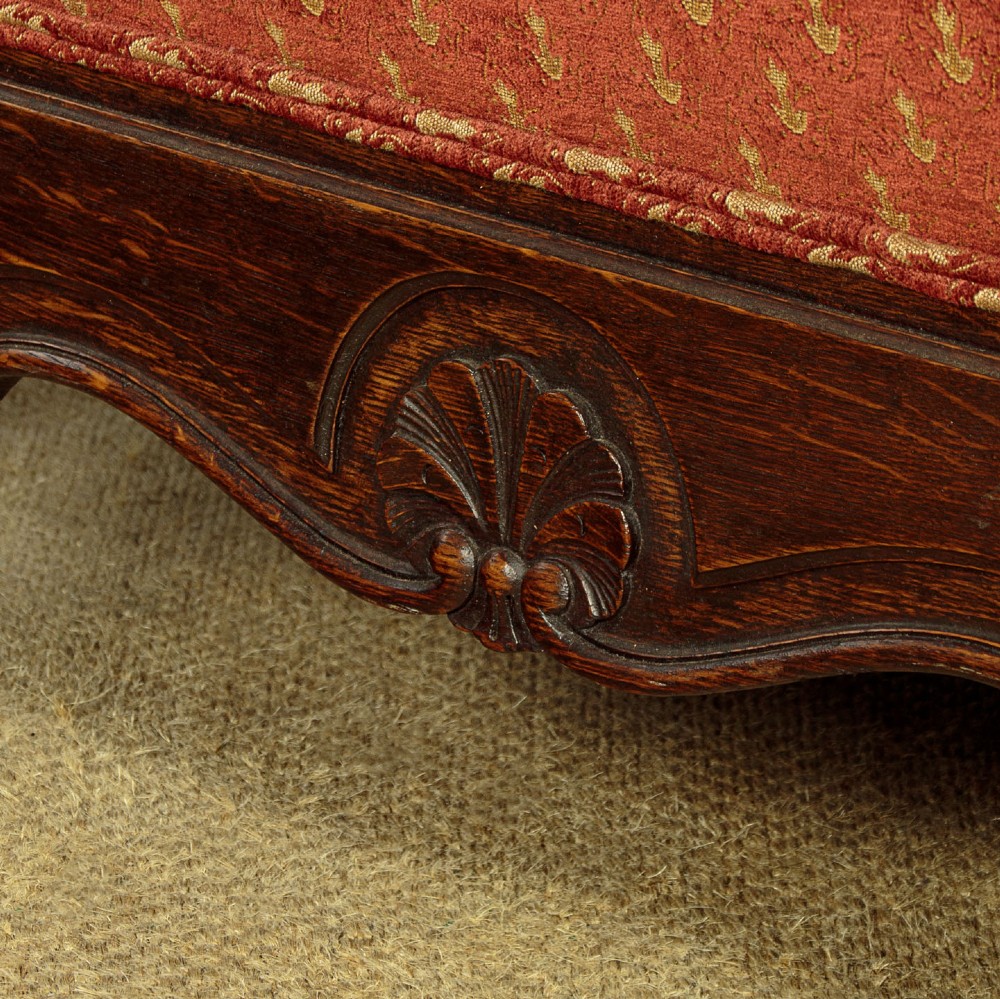 A c.1920 French-style upholstered day bed featuring a dark carved wooden frame, terracotta red patterned fabric, and matching tassel-trimmed cushions. View XIV