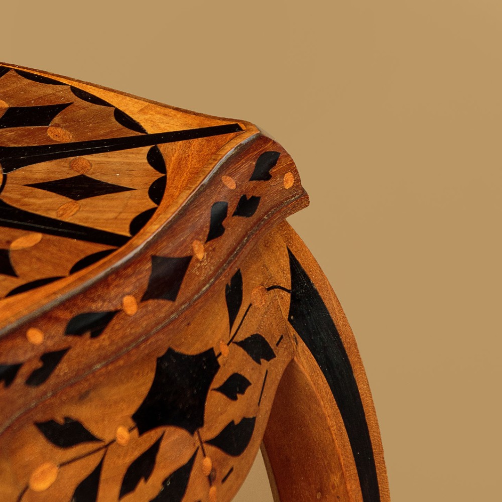 A tall, slender Edwardian specimen wood plant stand featuring geometric marquetry inlay on the top, apron, and legs, supported by four gently sweeping legs joined by an inlaid cross-stretcher. View V