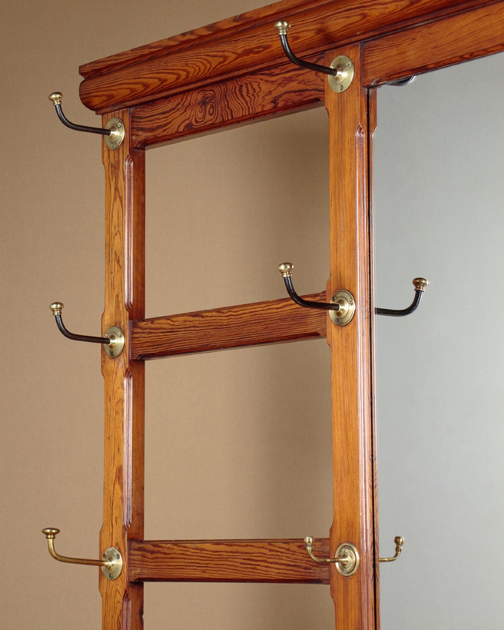 A large Victorian pine hallstand featuring a central vertical mirror, multiple brass coat hooks, inset ceramic tiles, a marble-topped glove drawer, and lower umbrella stand trays. View IV
