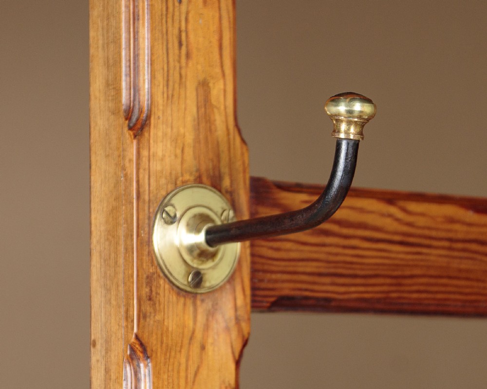 A large Victorian pine hallstand featuring a central vertical mirror, multiple brass coat hooks, inset ceramic tiles, a marble-topped glove drawer, and lower umbrella stand trays. View VI