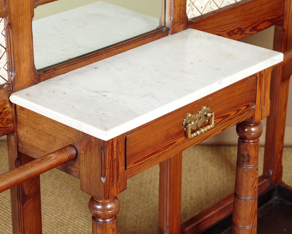 A large Victorian pine hallstand featuring a central vertical mirror, multiple brass coat hooks, inset ceramic tiles, a marble-topped glove drawer, and lower umbrella stand trays. View VII