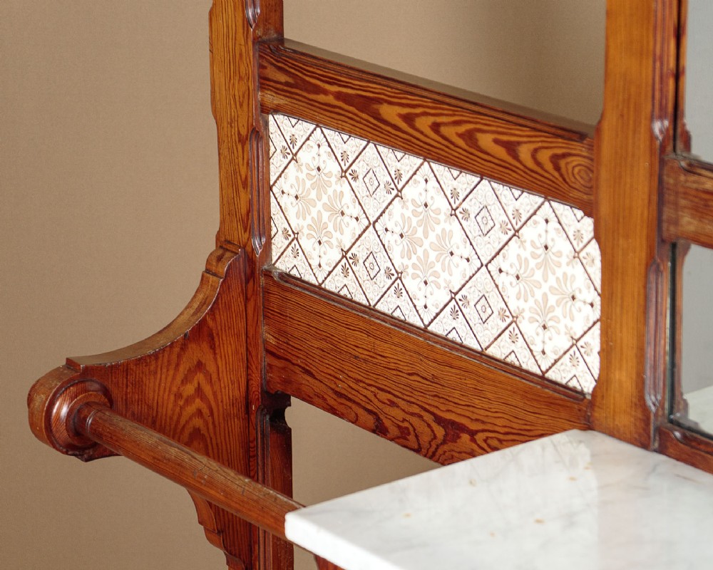 A large Victorian pine hallstand featuring a central vertical mirror, multiple brass coat hooks, inset ceramic tiles, a marble-topped glove drawer, and lower umbrella stand trays. View IX