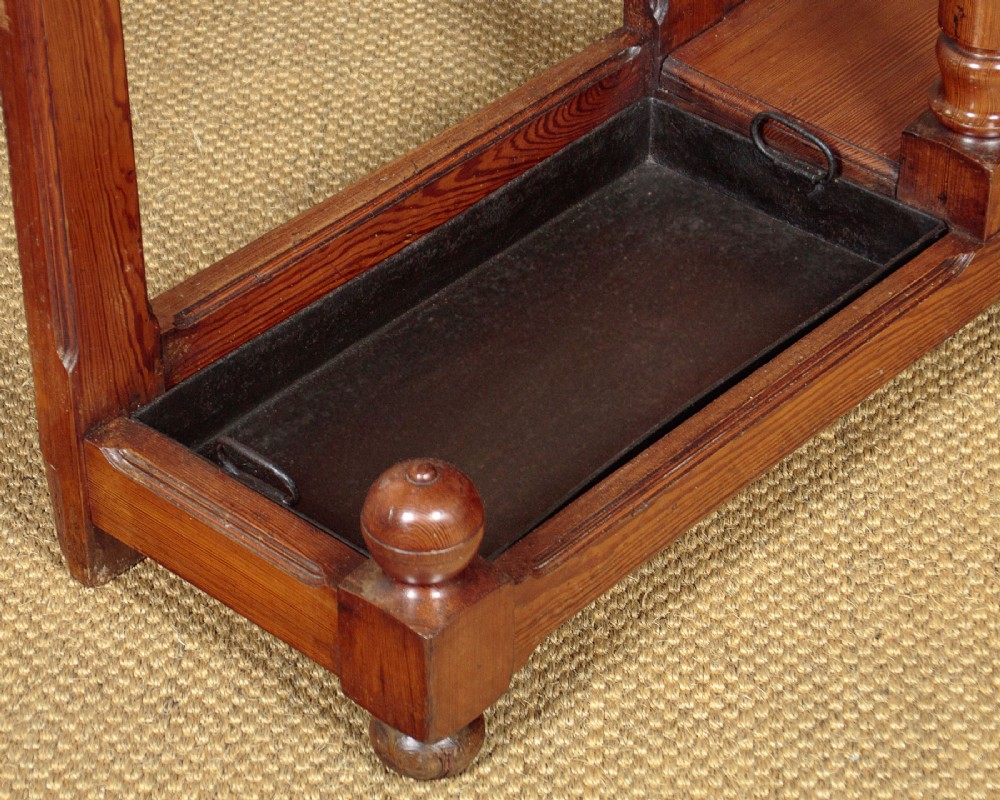 A large Victorian pine hallstand featuring a central vertical mirror, multiple brass coat hooks, inset ceramic tiles, a marble-topped glove drawer, and lower umbrella stand trays. View XIII