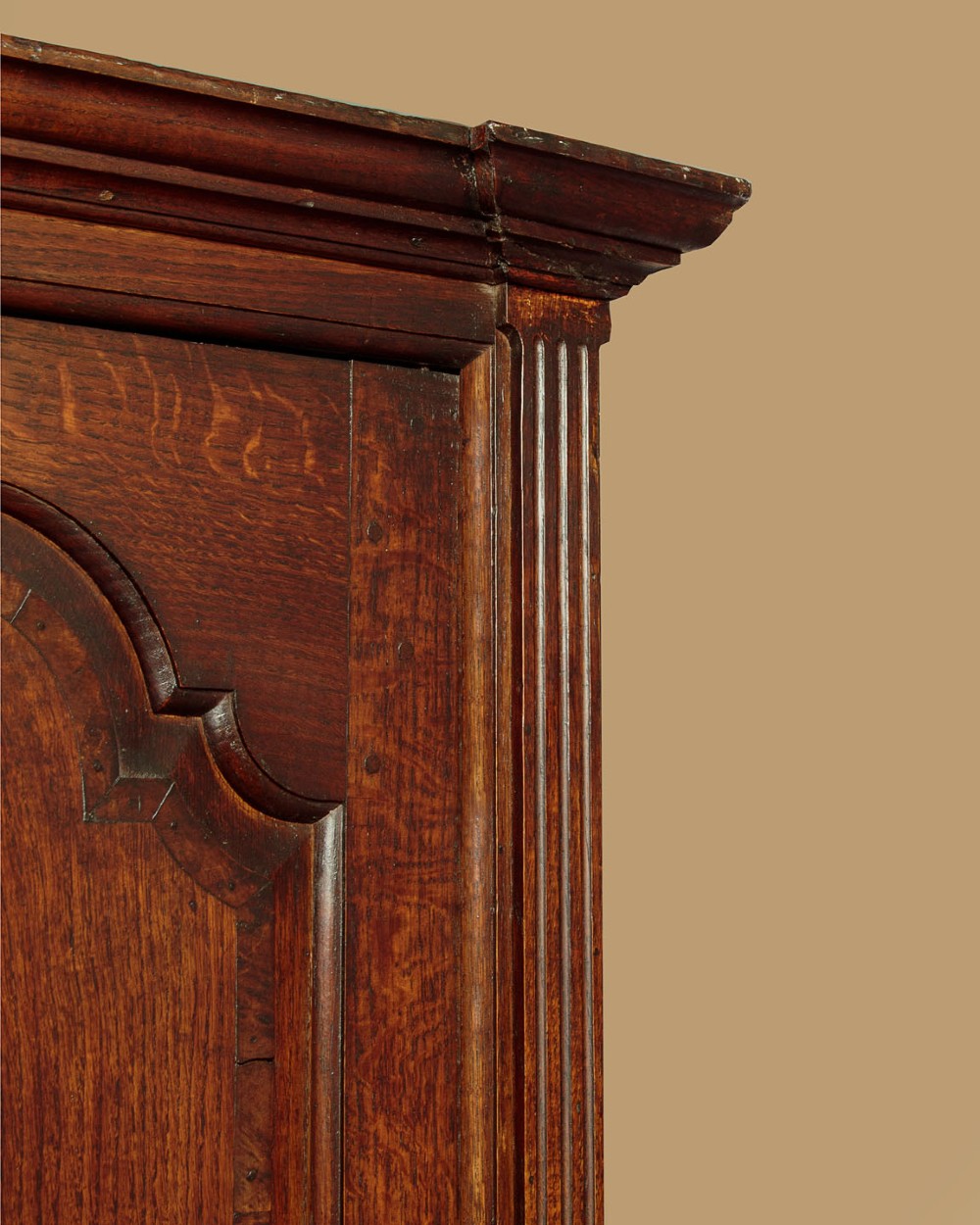A tall 18th-century dark oak Georgian tack cupboard featuring twin arched panel doors over a base with five drawers and brass handles. View VI