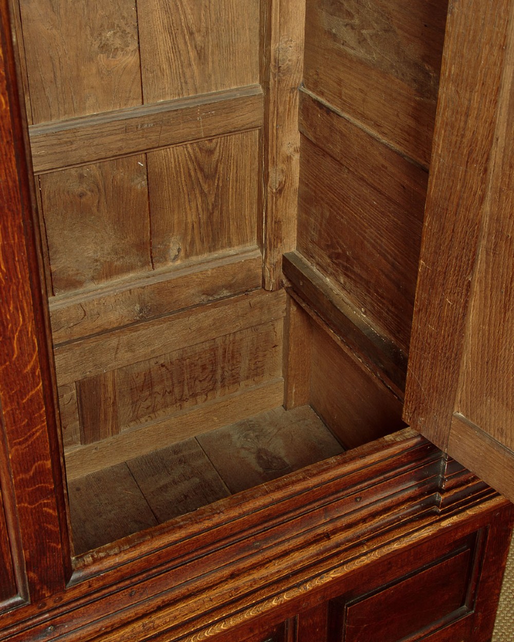A tall 18th-century dark oak Georgian tack cupboard featuring twin arched panel doors over a base with five drawers and brass handles. View XI