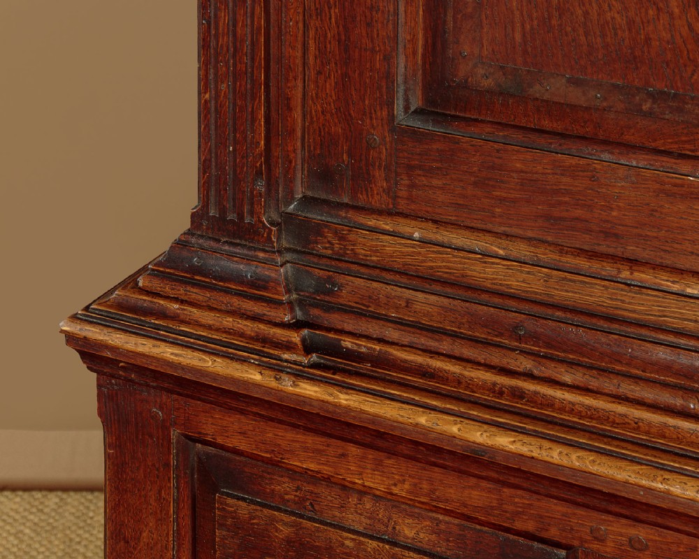 A tall 18th-century dark oak Georgian tack cupboard featuring twin arched panel doors over a base with five drawers and brass handles. View XII