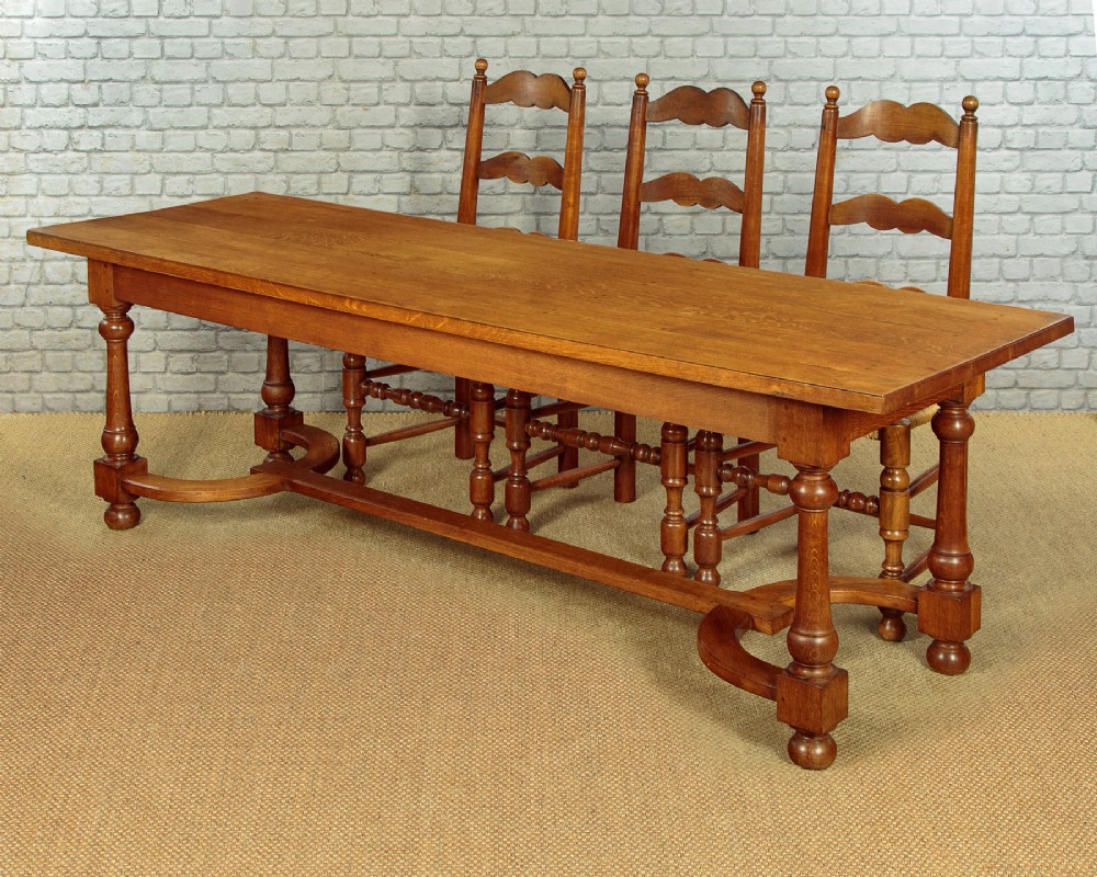 A long solid oak refectory dining table featuring turned legs and a low curved stretcher base. View II