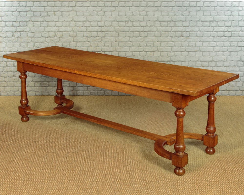 A long solid oak refectory dining table featuring turned legs and a low curved stretcher base. View III