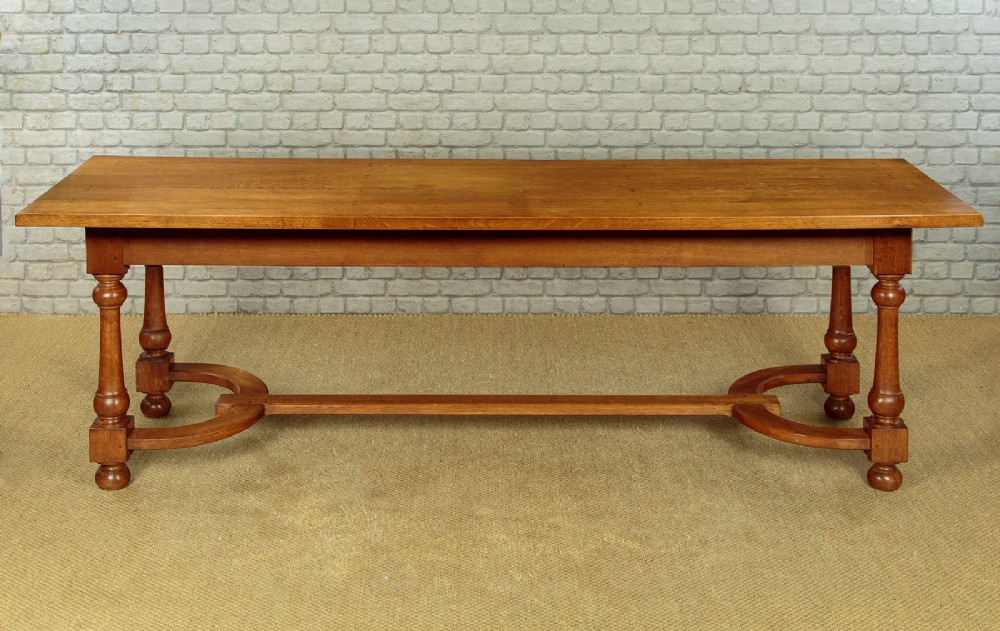A long solid oak refectory dining table featuring turned legs and a low curved stretcher base. View IV