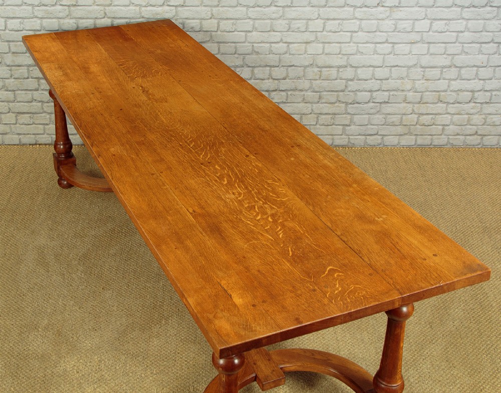A long solid oak refectory dining table featuring turned legs and a low curved stretcher base. View V