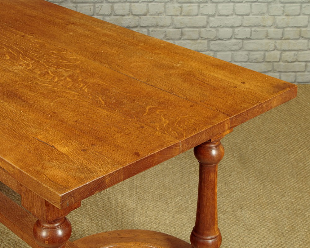 A long solid oak refectory dining table featuring turned legs and a low curved stretcher base. View VII
